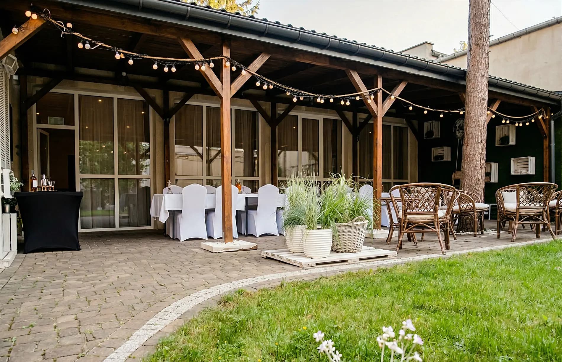 Zadaszona terasa z lampionami — elegancko nakryte stoły z wiklinowymi krzesłami